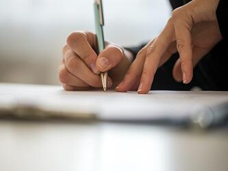 hands signing document with pen
